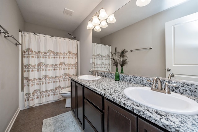 bathroom featuring toilet, double vanity, visible vents, and a sink