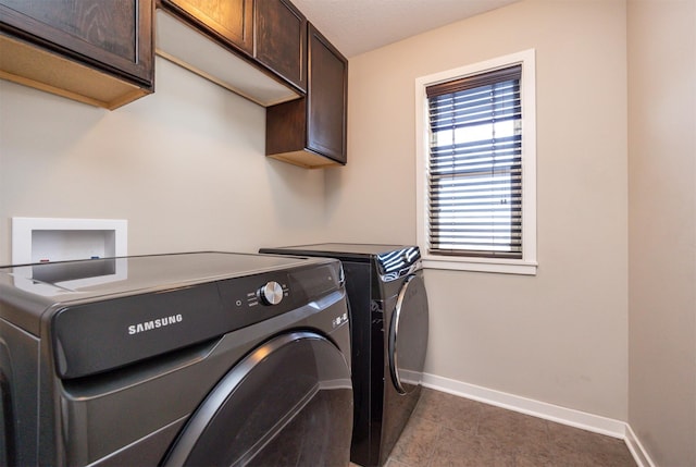 laundry room featuring cabinet space, dark tile patterned floors, baseboards, and washer and clothes dryer