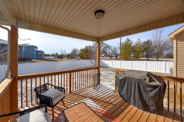 snow covered deck with grilling area and a fenced backyard