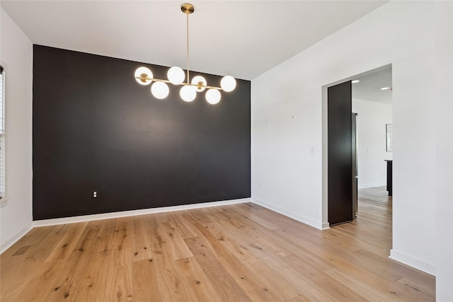16924 Prairie Dr, Clive, IA 50325 - spare room with a chandelier, light wood finished floors, and an accent wall