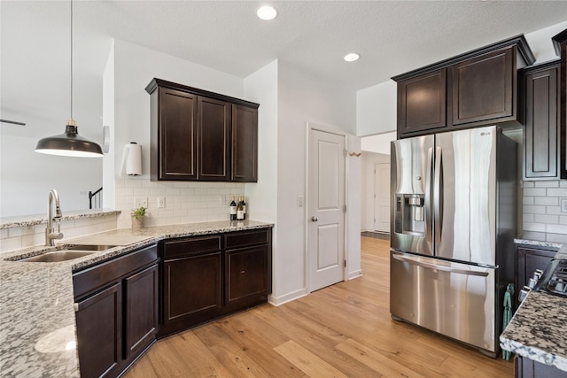 16924 Prairie Dr, Clive, IA 50325 - kitchen with stainless steel fridge, light wood-style flooring, backsplash, dark brown cabinetry, and light stone counters