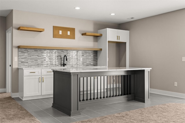 kitchen with tile patterned flooring, white cabinetry, sink, and decorative backsplash