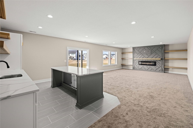 kitchen featuring light stone counters, light colored carpet, sink, and a kitchen island