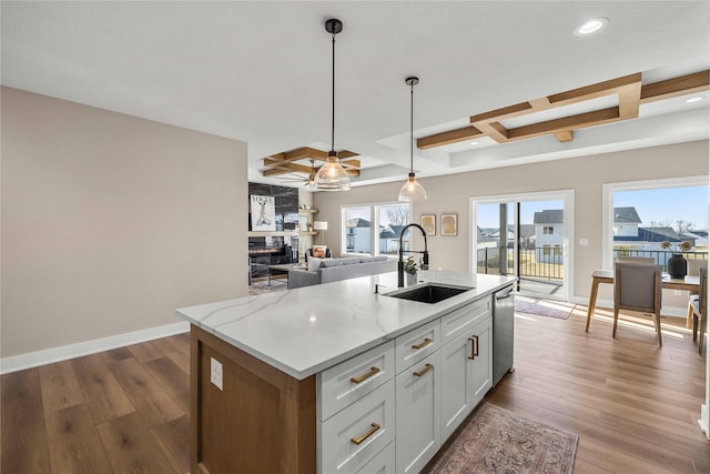 kitchen with sink, decorative light fixtures, beamed ceiling, light stone countertops, and white cabinets