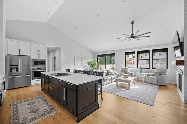 kitchen with white cabinets, a kitchen bar, a center island, light hardwood / wood-style floors, and stainless steel appliances