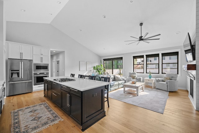 kitchen featuring stainless steel appliances, white cabinets, a center island, and light wood-style flooring