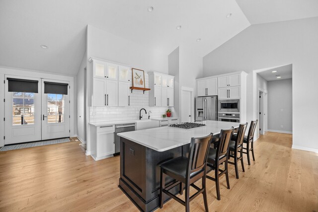 kitchen with a breakfast bar, white cabinetry, a center island, light hardwood / wood-style flooring, and appliances with stainless steel finishes