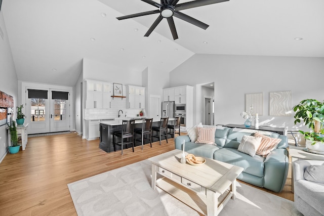 living room featuring ceiling fan, high vaulted ceiling, and light wood-style floors