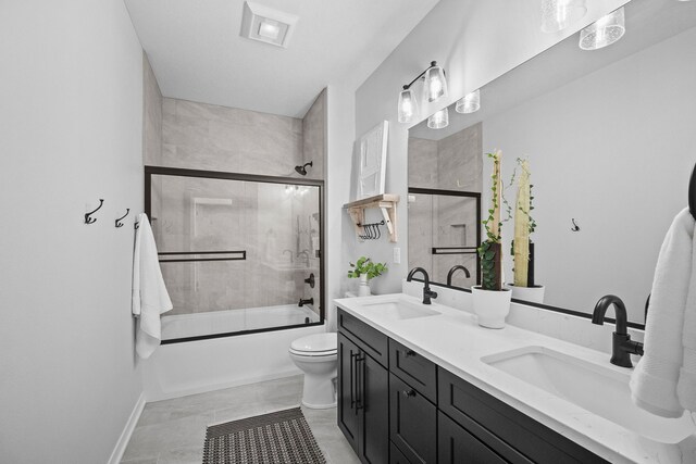 full bathroom with vanity, bath / shower combo with glass door, and toilet