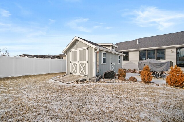 back of house with a storage shed