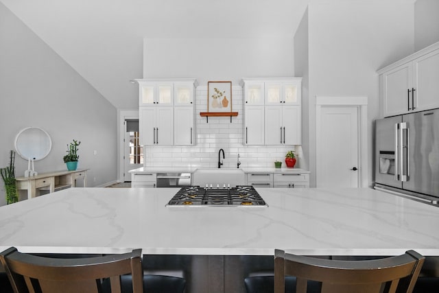 kitchen with a breakfast bar area, decorative backsplash, a large island, stainless steel appliances, and a sink