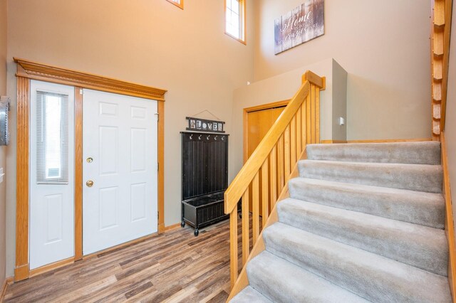 entrance foyer with stairs, a high ceiling, and wood finished floors