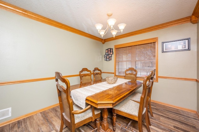 dining space featuring visible vents, ornamental molding, an inviting chandelier, wood finished floors, and a textured ceiling