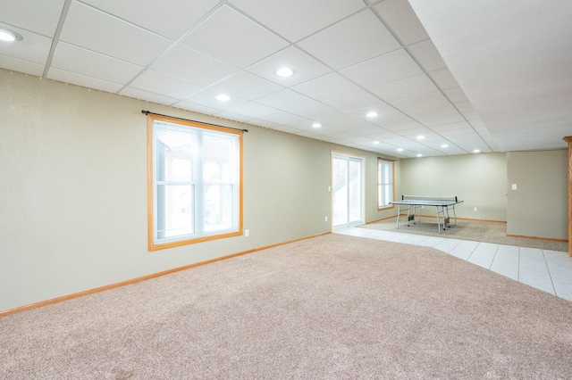 interior space with a paneled ceiling, light colored carpet, and a healthy amount of sunlight