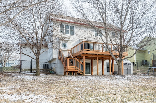 snow covered back of property with an outbuilding, fence, a shed, stairs, and a trampoline