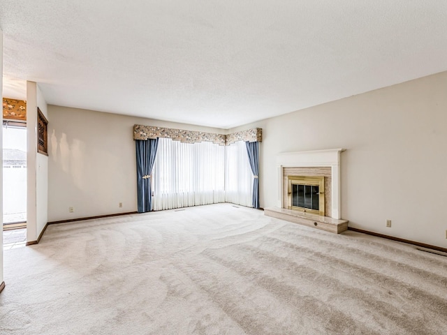 unfurnished living room with light carpet, a textured ceiling, a high end fireplace, and baseboards