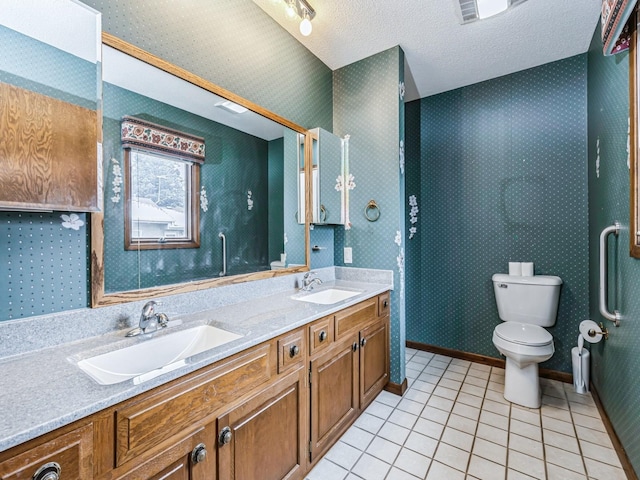 bathroom featuring a textured ceiling, tile patterned floors, a sink, and wallpapered walls