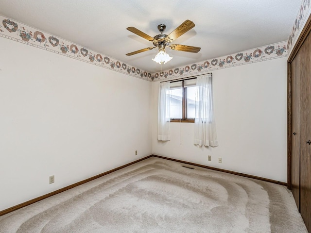 empty room featuring baseboards, ceiling fan, visible vents, and light colored carpet