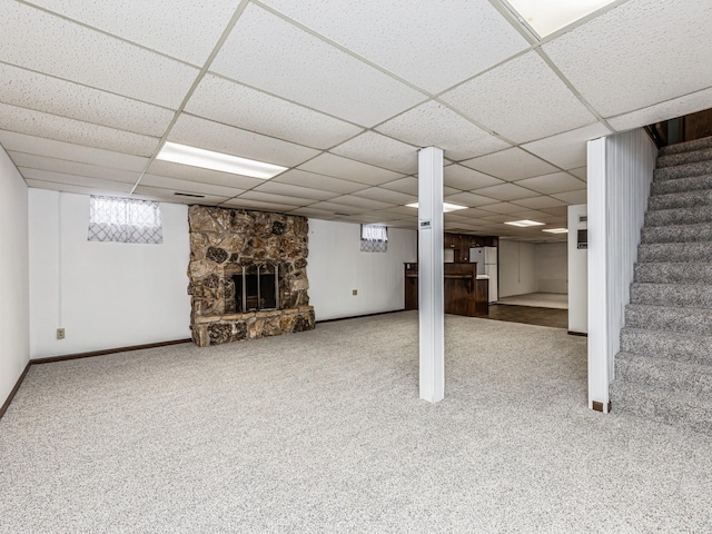 basement with a fireplace, freestanding refrigerator, carpet flooring, a drop ceiling, and stairs