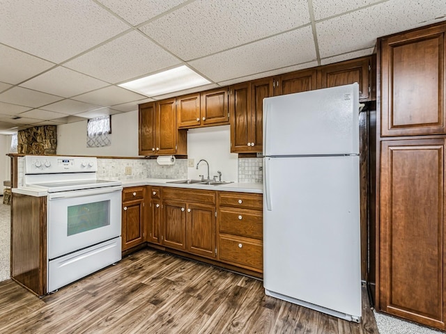 kitchen with white appliances, a sink, light countertops, brown cabinetry, and dark wood finished floors