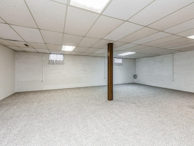 finished basement featuring brick wall and a drop ceiling