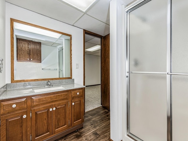 full bathroom with a shower stall, wood finished floors, a drop ceiling, and vanity