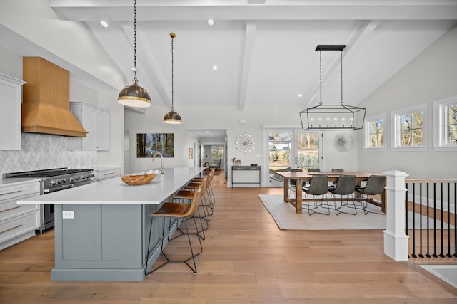 kitchen featuring white cabinetry, high end stove, pendant lighting, a large island, and decorative backsplash