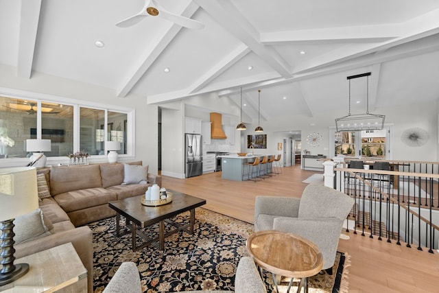 living room featuring ceiling fan, vaulted ceiling with beams, and light wood-type flooring