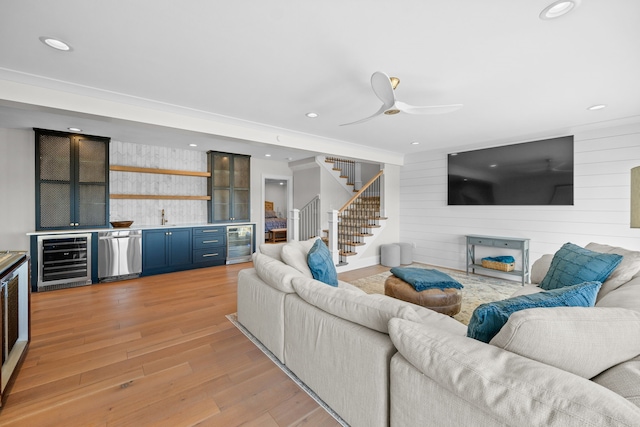 living room featuring wine cooler, wood walls, bar area, and light wood-type flooring