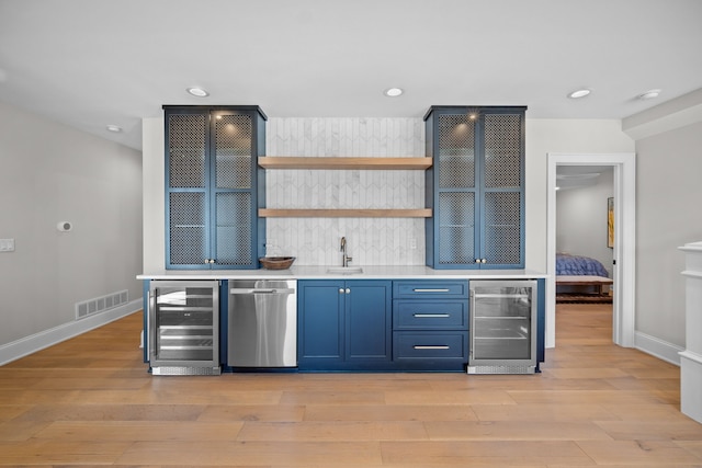 bar with blue cabinets, beverage cooler, dishwasher, and sink