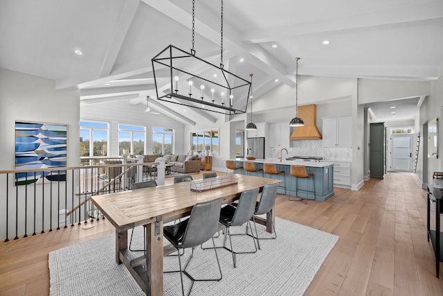 dining room with high vaulted ceiling, sink, beam ceiling, and light hardwood / wood-style floors