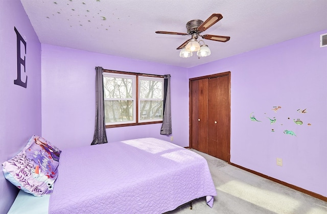 bedroom featuring ceiling fan, light colored carpet, a closet, and a textured ceiling