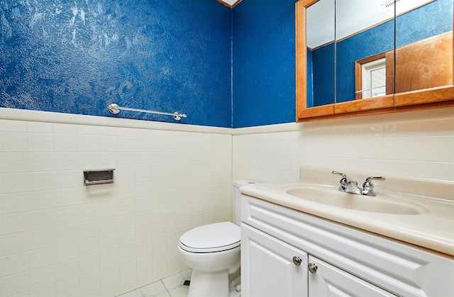 bathroom with vanity, toilet, tile patterned flooring, and tile walls