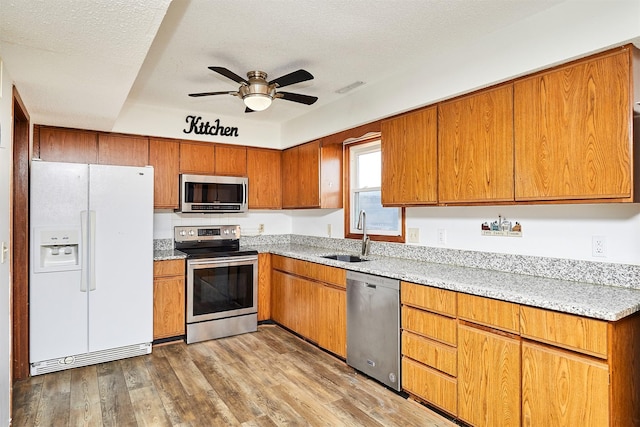 kitchen with sink, light hardwood / wood-style floors, a textured ceiling, and appliances with stainless steel finishes