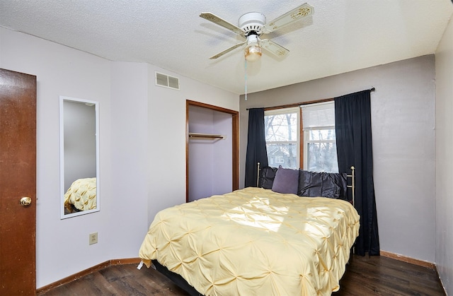 bedroom with dark wood-type flooring, ceiling fan, a closet, and a textured ceiling