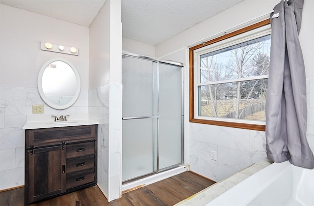 bathroom with a shower with door, tile walls, and a textured ceiling