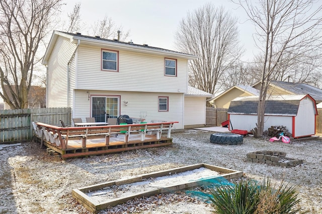 rear view of property with a wooden deck, a fire pit, and a storage shed