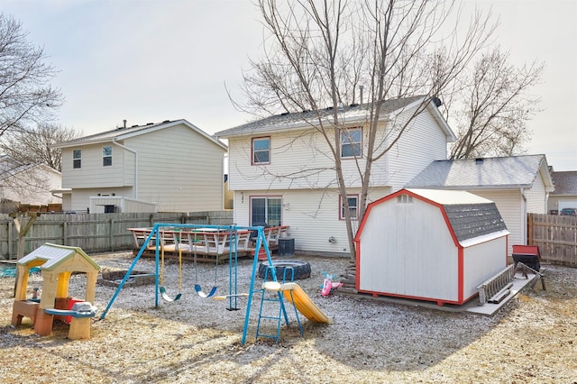 rear view of property with a trampoline, a playground, and a shed