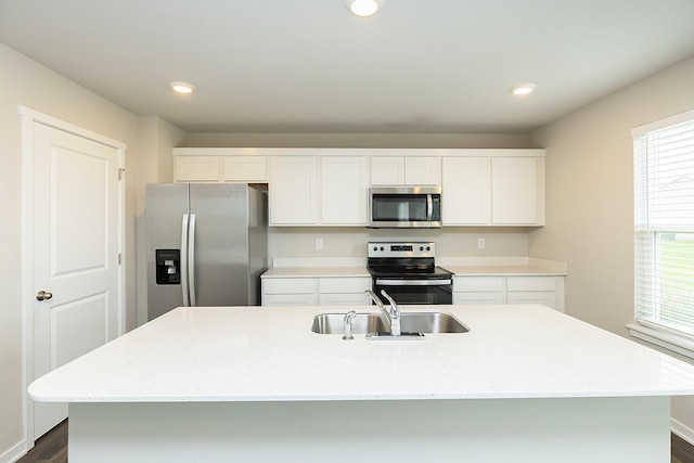 kitchen with sink, white cabinetry, appliances with stainless steel finishes, dark hardwood / wood-style flooring, and an island with sink