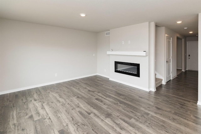 unfurnished living room with visible vents, baseboards, recessed lighting, wood finished floors, and a glass covered fireplace