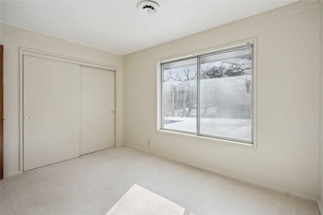 unfurnished bedroom with light colored carpet and a closet