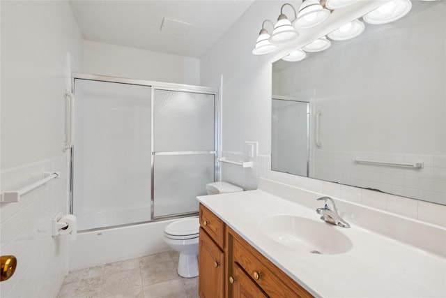 full bathroom featuring tile walls, vanity, enclosed tub / shower combo, and toilet