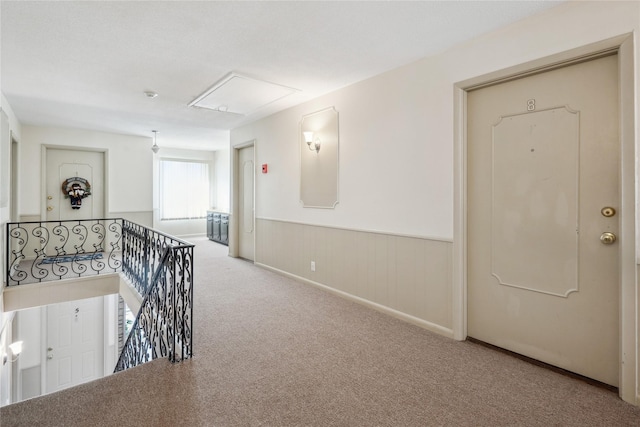 hallway with light colored carpet and wood walls