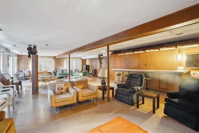 living room featuring plenty of natural light, wooden walls, and decorative columns