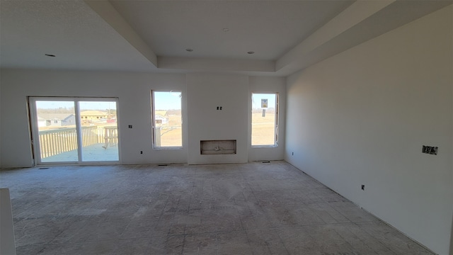 unfurnished living room with light carpet and a raised ceiling