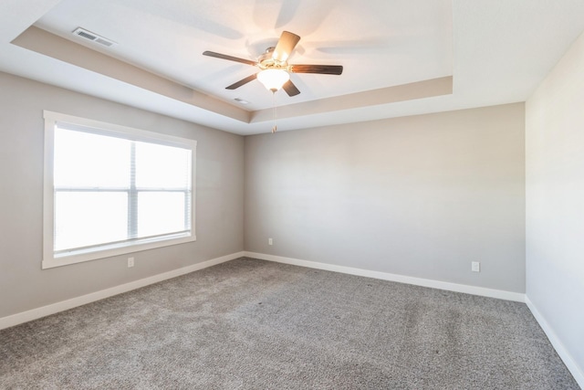 empty room featuring ceiling fan, carpet flooring, and a tray ceiling