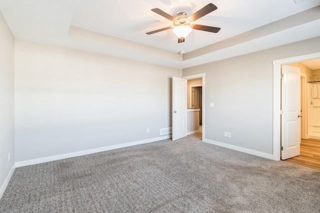 unfurnished room featuring a tray ceiling, ceiling fan, and carpet flooring