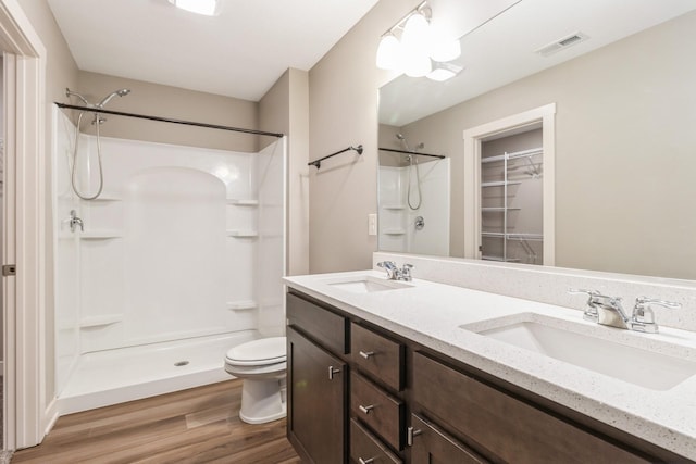 bathroom featuring vanity, hardwood / wood-style flooring, toilet, and a shower