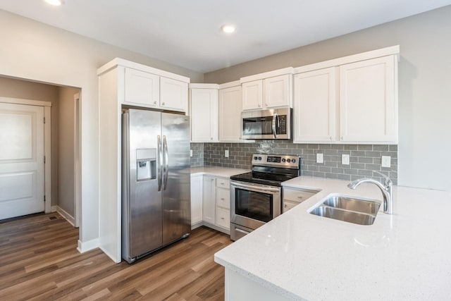 kitchen with hardwood / wood-style floors, tasteful backsplash, white cabinetry, sink, and stainless steel appliances