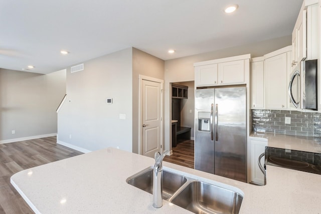 kitchen with sink, light stone counters, appliances with stainless steel finishes, white cabinets, and backsplash